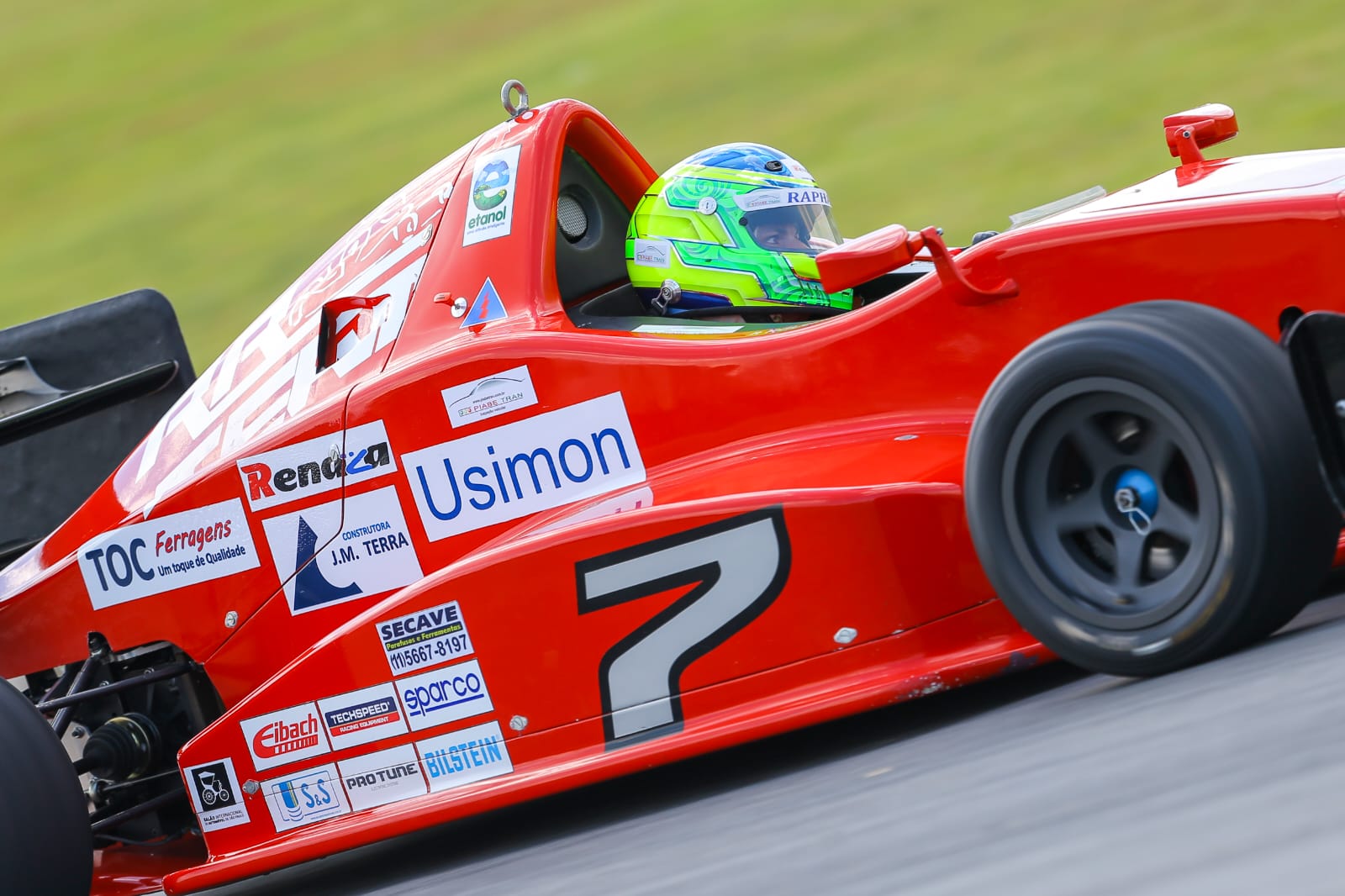 Carro de formula vermelho #7 em acao - vista lateral